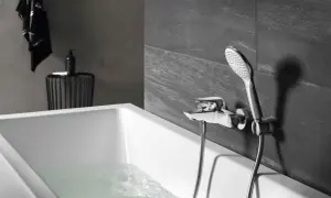 Elegancka bateria prysznicowa zamontowana na ścianie nad wanną, z której leje się woda.
