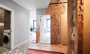 Przed i po remoncie starego domu. Widok na korytarz z pralką i łazienką po lewej, oraz odsłoniętą ceglaną ścianę i instalacje po prawej.