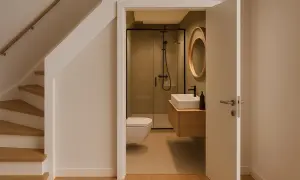 Nowoczesna łazienka z prysznicem, wiszącym wc i umywalką na jednej ścianie. Obok schody.