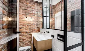 Nowoczesna łazienka w stylu loft z ceglaną ścianą, drewnianą szafką pod umywalkę i czarnymi metalowymi elementami.