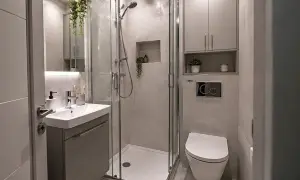 Nowoczesna, mała łazienka w bloku 2m2. Kabina prysznicowa, umywalka i wisząca miska WC. Jasne płytki i wiszące rośliny dodają świeżości.