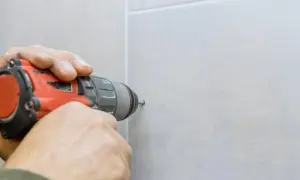 Precyzyjne wiercenie w gresie za pomocą wiertarki. Dłoń trzyma narzędzie, tworząc otwór w płytce.