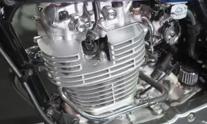 Silnik motocyklowy, prawdopodobnie 2 suw a 4 suw, z widocznymi żebrowaniami cylindra, świecą metalowymi elementami i czarną ramą.