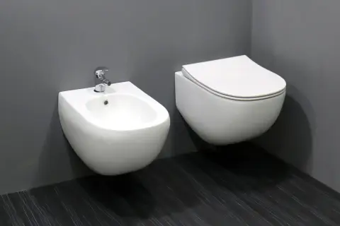 Biała, wisząca ceramika łazienkowa: bidet z baterią i przylegająca do niego miska WC.