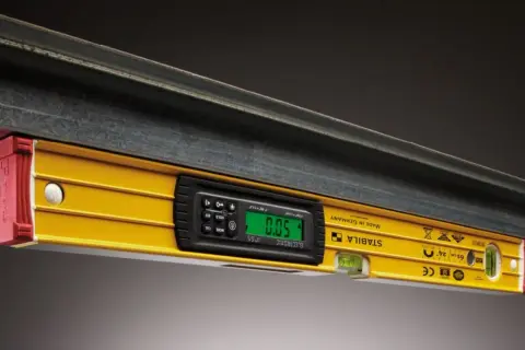 Żółta poziomica elektroniczna STABILA z cyfrowym wyświetlaczem pokazuje 0.05. To jedne z precyzyjnych przyrządów pomiarowych.
