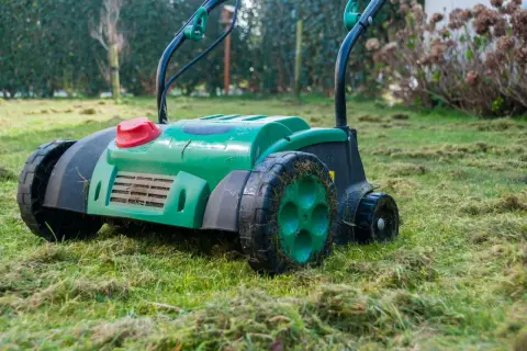 Zielony aerator na trawniku, gotowy do pracy. Zastanawiasz się, aerator co to? To urządzenie do napowietrzania gleby.