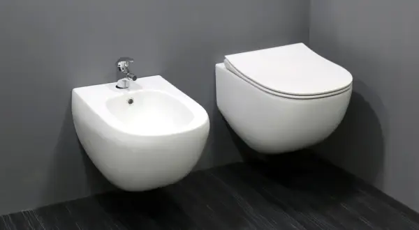Biała, wisząca ceramika łazienkowa: bidet z baterią i przylegająca do niego miska WC.