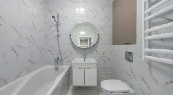 Nowoczesna łazienka z wanną, umywalką i podwieszanym WC. Płytki imitujące marmur dodają elegancji.