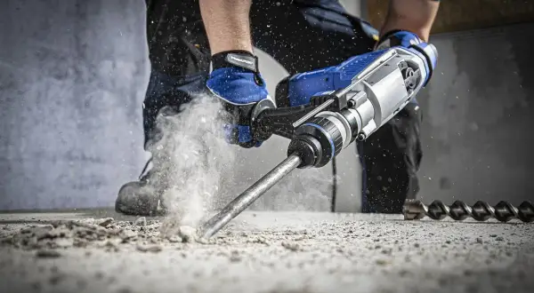 Mocna wiertarka udarowa kruszy beton, generując pył. To właśnie jest udar w wiertarce – siła uderzeń.