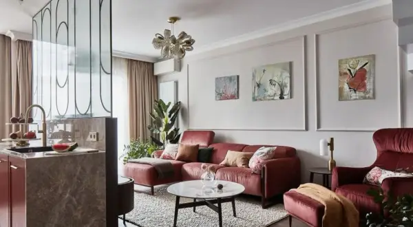 Elegancka ściana w salonie z sofą w kolorze cegły, obrazami i designerską lampą.