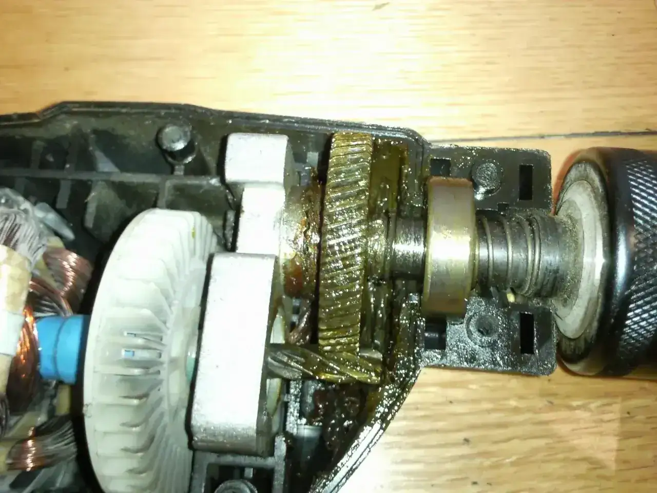 Wiertarka z widocznym uzwojeniem silnika, wentylatorem i przekładnią. Smar na zębatkach sugeruje, co to jest udar w wiertarce – mechanizm napędzający.