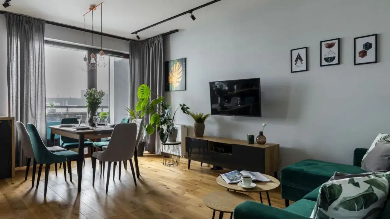 Zielone akcenty i rośliny ożywiają ten szary salon. Elegancka jadalnia i wygodna strefa relaksu.