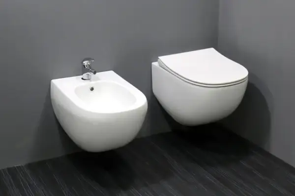 Biała, wisząca ceramika łazienkowa: bidet z baterią i przylegająca do niego miska WC.