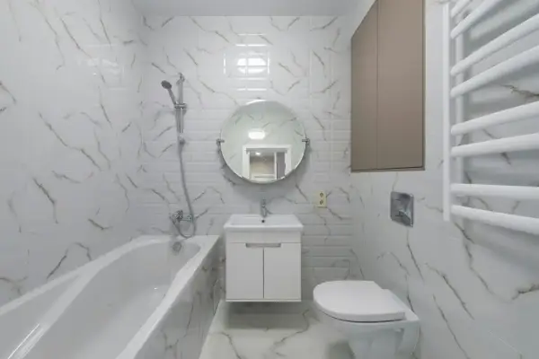 Nowoczesna łazienka z wanną, umywalką i podwieszanym WC. Płytki imitujące marmur dodają elegancji.