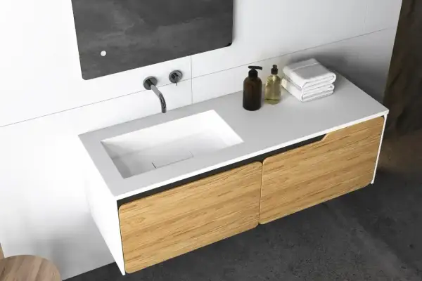 Nowoczesny montaż szafki wiszącej pod umywalkę z frontami imitującymi drewno. Eleganckie, minimalistyczne rozwiązanie do łazienki.