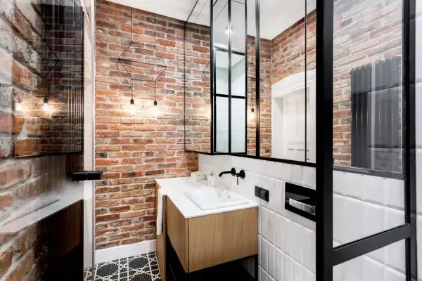 Nowoczesna łazienka w stylu loft z ceglaną ścianą, drewnianą szafką pod umywalkę i czarnymi metalowymi elementami.