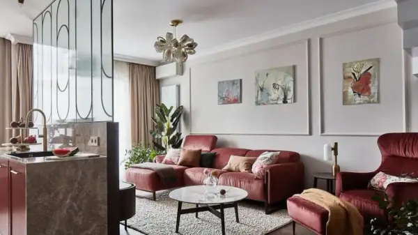 Elegancka ściana w salonie z sofą w kolorze cegły, obrazami i designerską lampą.