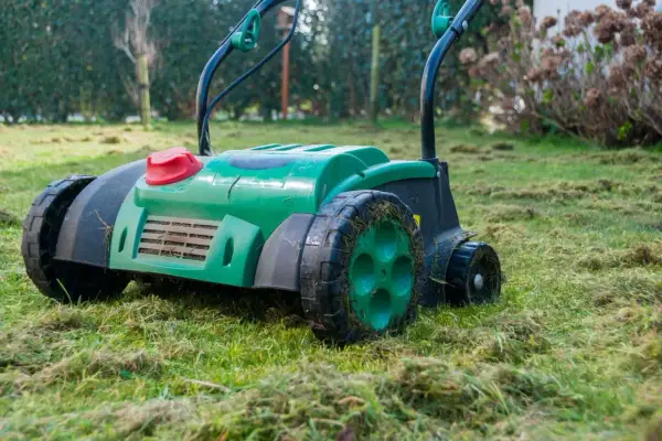 Zielony aerator na trawniku, gotowy do pracy. Zastanawiasz się, aerator co to? To urządzenie do napowietrzania gleby.